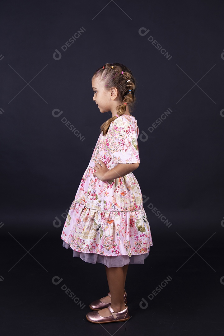 Linda menina usando vestido florido sobre um fundo isolado preto.