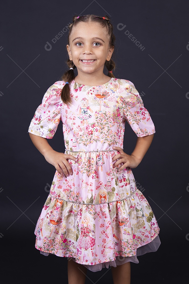 Linda menina usando vestido florido sobre um fundo isolado preto.