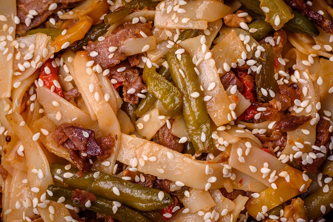 Delicioso prato asiático udon com pimenta, feijão verde, especiarias e ervas em uma placa cerâmica sobre um fundo escuro de concreto