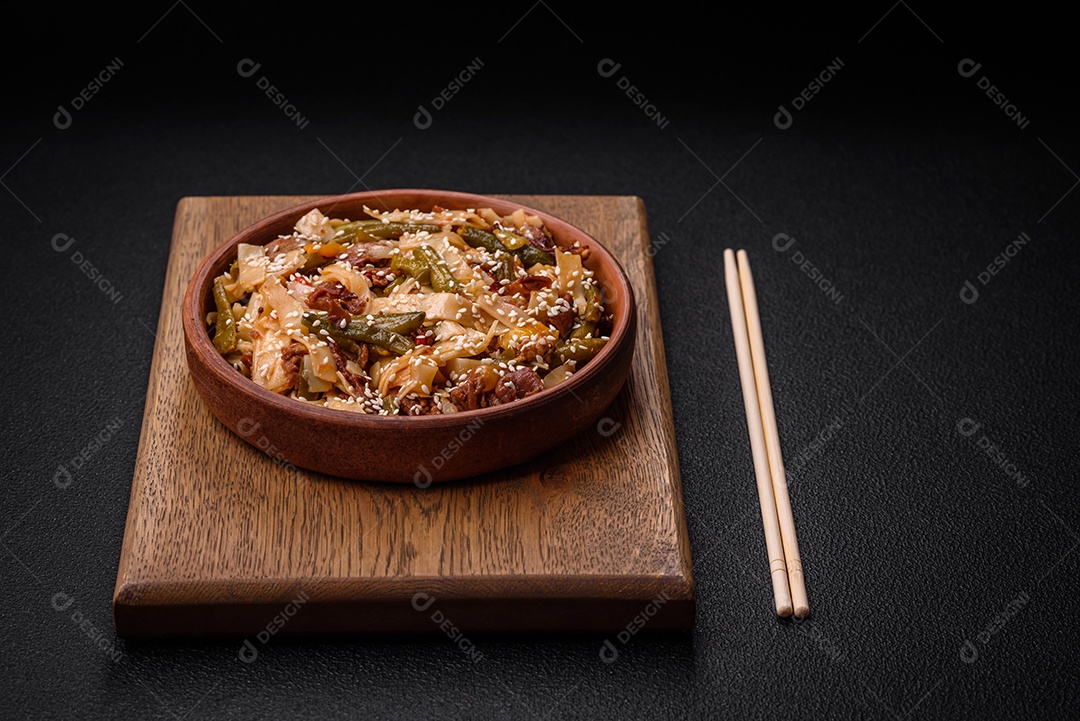 Delicioso prato asiático udon com pimenta, feijão verde, especiarias e ervas em uma placa cerâmica sobre um fundo escuro de concreto