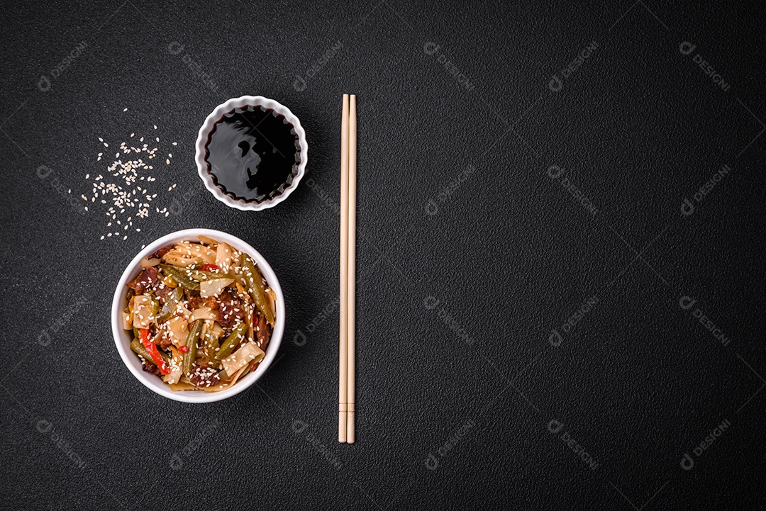 Delicioso prato asiático udon com pimenta, feijão verde, especiarias e ervas em uma placa cerâmica sobre um fundo escuro de concreto