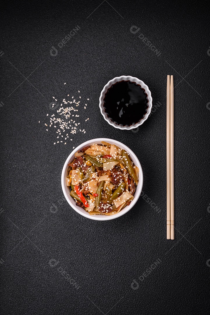 Delicioso prato asiático udon com pimenta, feijão verde, especiarias e ervas em uma placa cerâmica sobre um fundo escuro de concreto