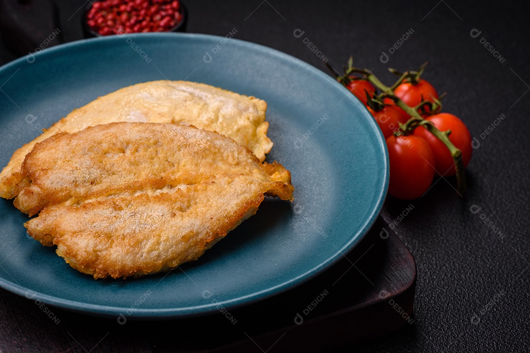 Deliciosas costeletas de peito de frango empanadas com sal, especiarias e ervas sobre um fundo escuro de concreto