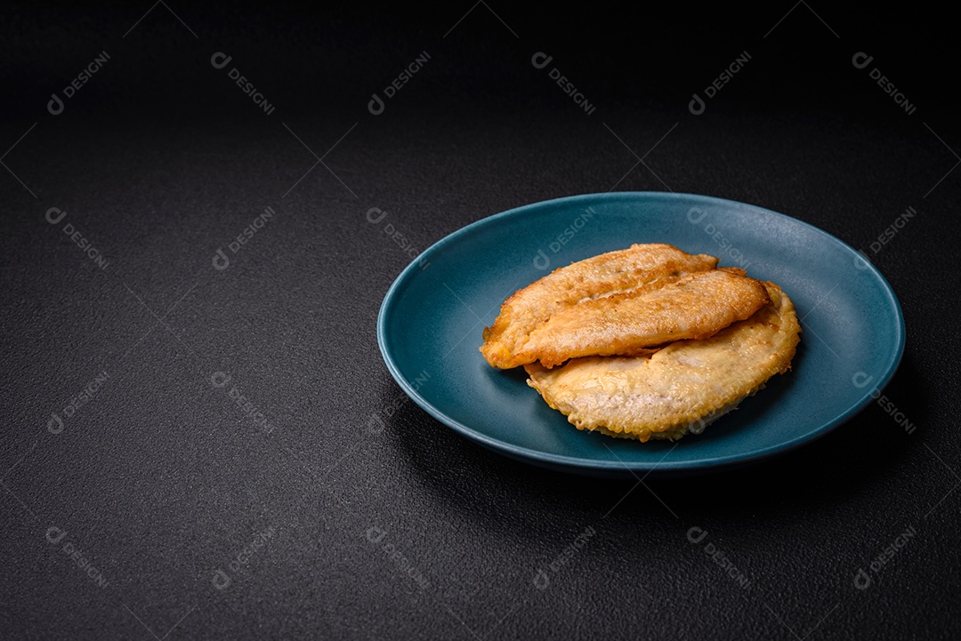 Deliciosas costeletas de peito de frango empanadas com sal, especiarias e ervas sobre um fundo escuro de concreto