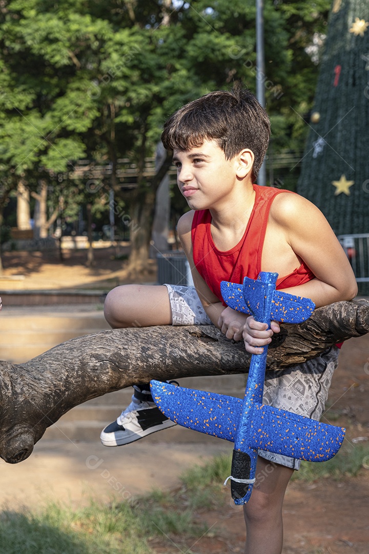 Criança brasileira de 10 anos brincando com seu aviãozinho de isopor em uma tarde ensolarada.