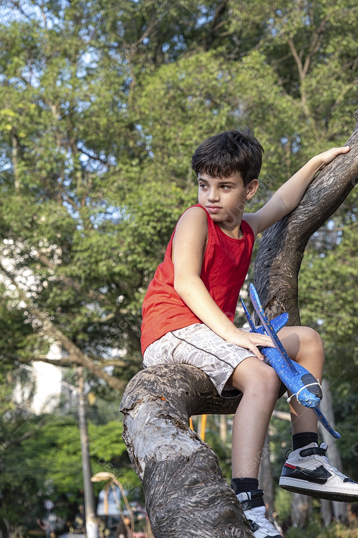 Criança brasileira de 10 anos brincando com seu aviãozinho de isopor em uma tarde ensolarada.