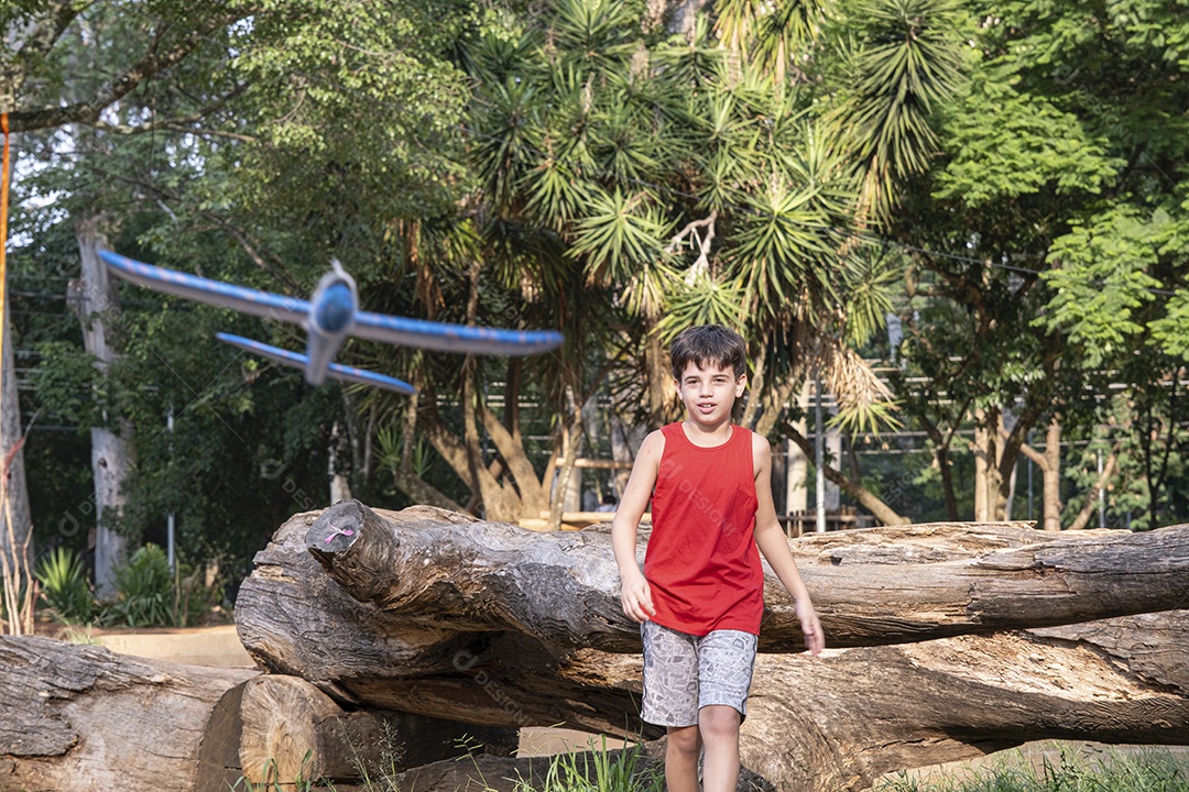 Criança brasileira de 10 anos brincando com seu aviãozinho de isopor em uma tarde ensolarada.