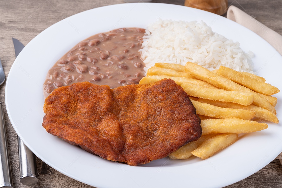 Carne à milanesa, arroz, feijão e batata frita sobre a mesa