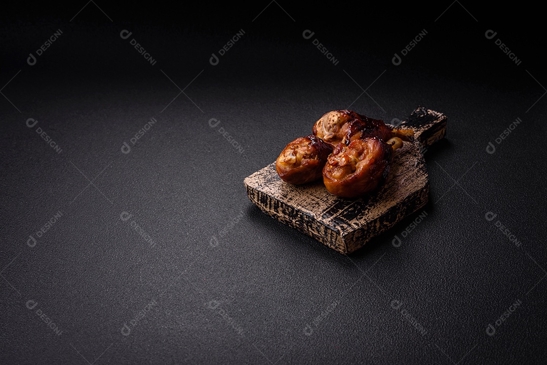 Deliciosos champignon inteiros e suculentos assados ​​na grelha com sal e especiarias em uma placa de cerâmica sobre um fundo escuro de concreto