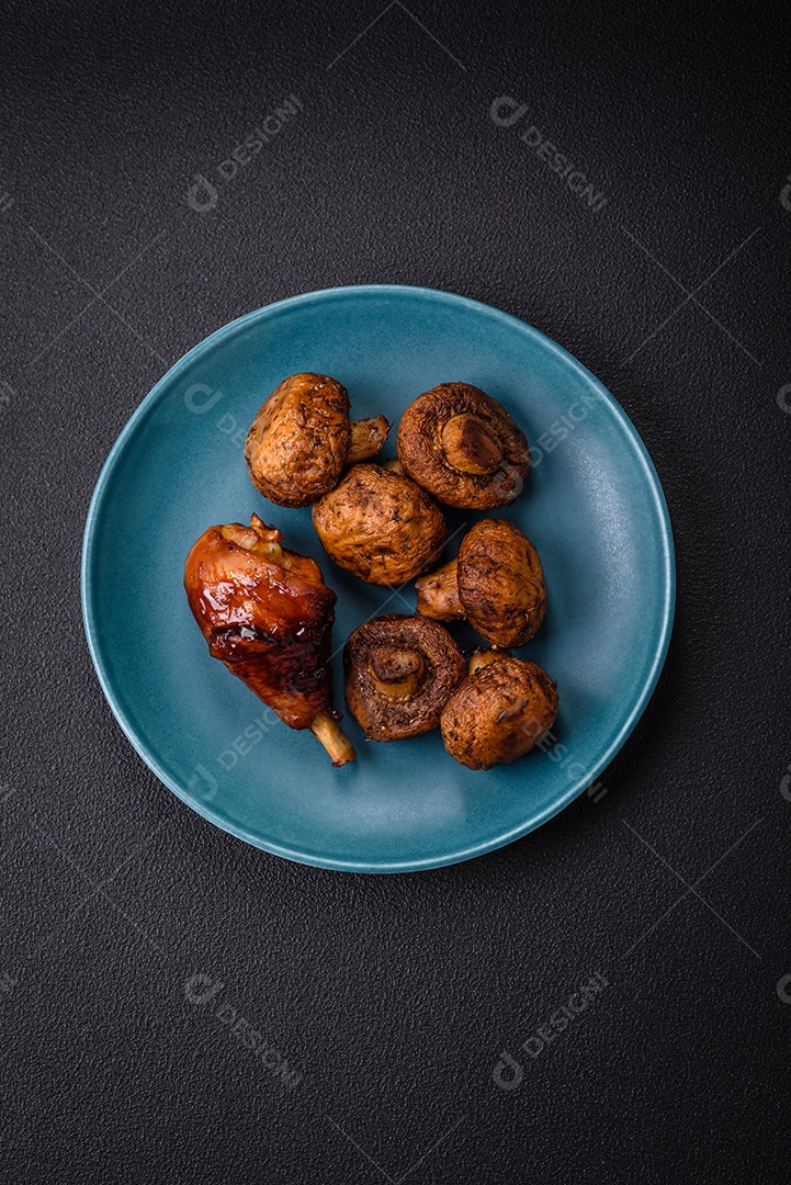 Deliciosos champignon inteiros e suculentos assados ​​na grelha com sal e especiarias em uma placa de cerâmica sobre um fundo escuro de concreto