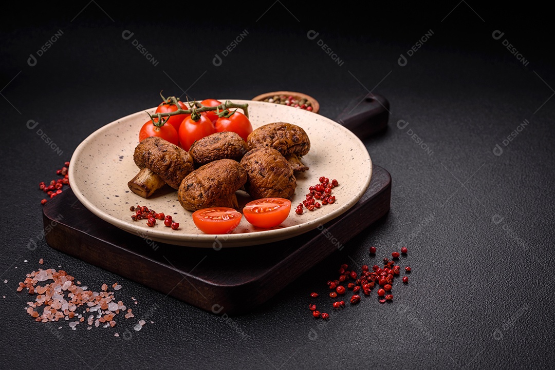Deliciosos champignon inteiros e suculentos assados ​​na grelha com sal e especiarias em uma placa de cerâmica sobre um fundo escuro de concreto