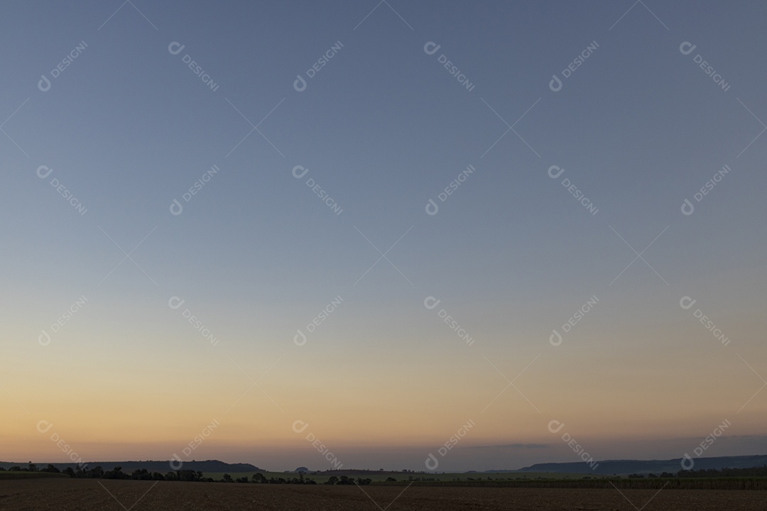 Sol está se pondo sobre campo arado