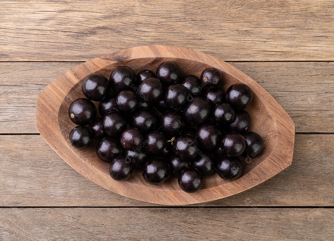 Travessa de madeira com jabuticaba dentro sobre fundo de madeira