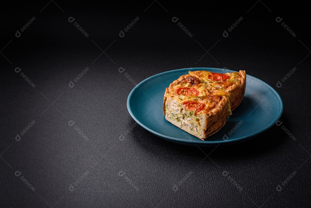 Deliciosa quiche com tomate, queijo, frango, especiarias e ervas sobre um fundo escuro de concreto