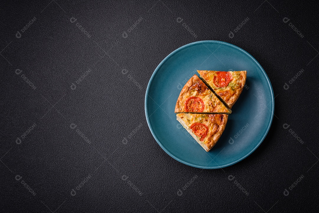 Deliciosa quiche com tomate, queijo, frango, especiarias e ervas sobre um fundo escuro de concreto