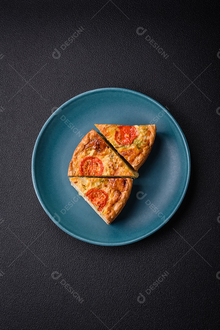 Deliciosa quiche com tomate, queijo, frango, especiarias e ervas sobre um fundo escuro de concreto