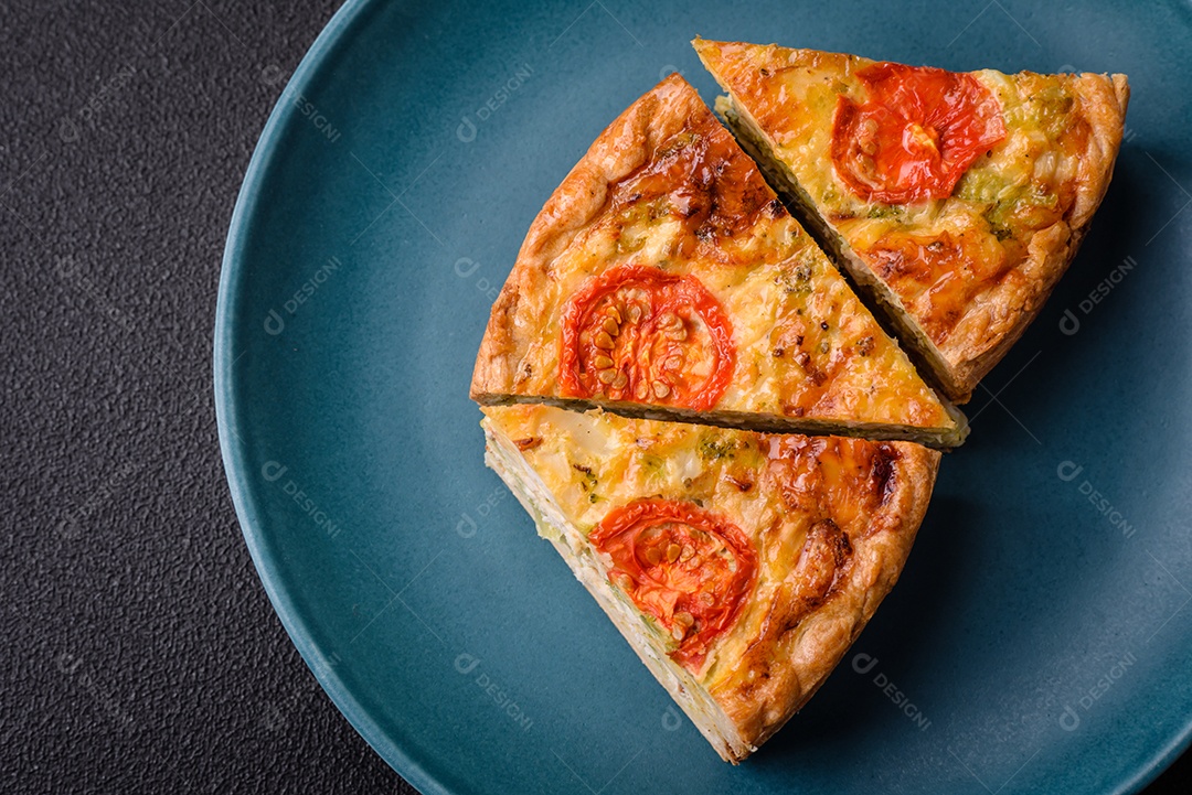 Deliciosa quiche com tomate, queijo, frango, especiarias e ervas sobre um fundo escuro de concreto