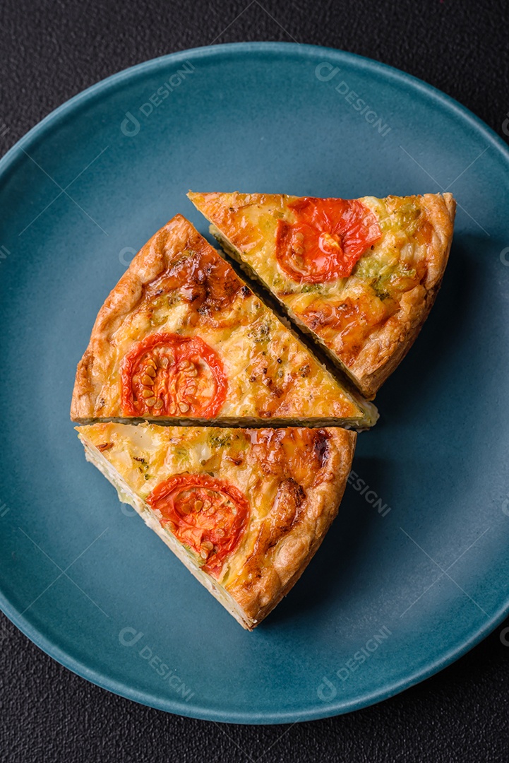 Deliciosa quiche com tomate, queijo, frango, especiarias e ervas sobre um fundo escuro de concreto