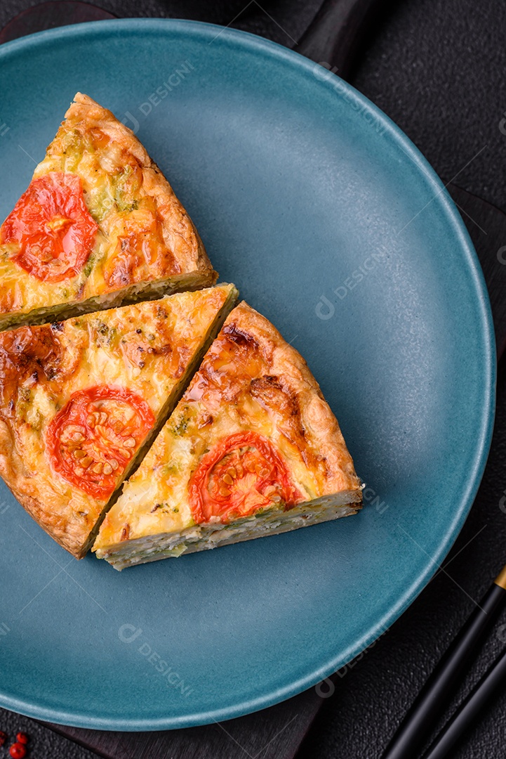 Deliciosa quiche com tomate, queijo, frango, especiarias e ervas sobre um fundo escuro de concreto