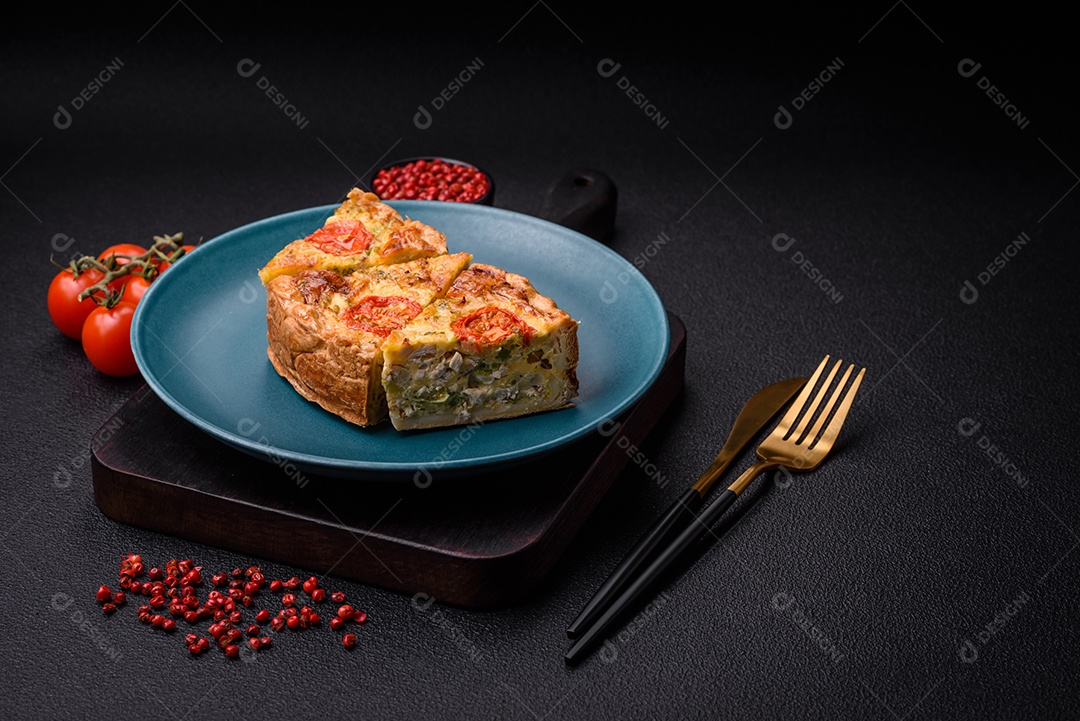 Deliciosa quiche com tomate, queijo, frango, especiarias e ervas sobre um fundo escuro de concreto