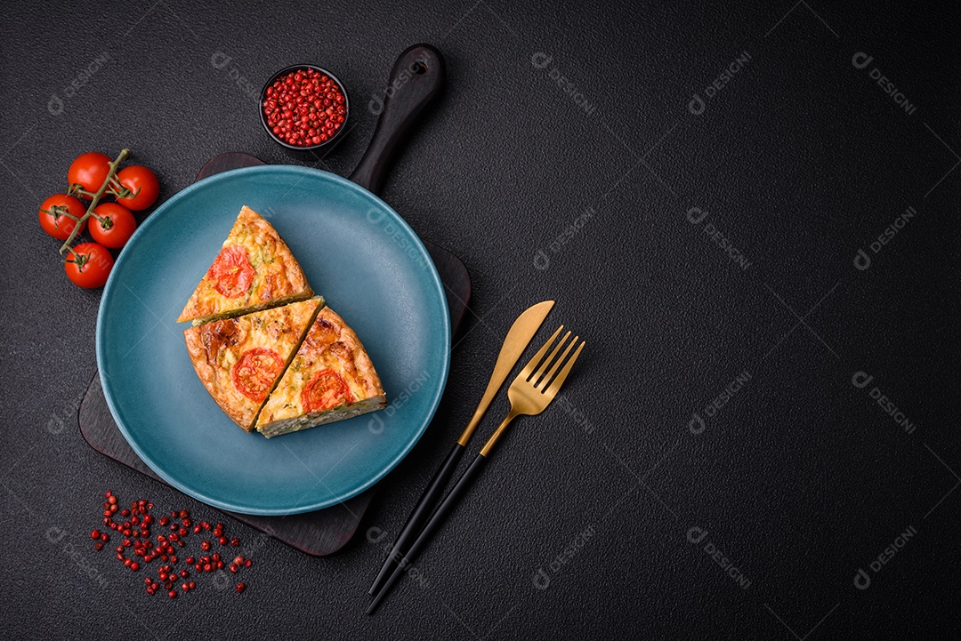 Deliciosa quiche com tomate, queijo, frango, especiarias e ervas sobre um fundo escuro de concreto