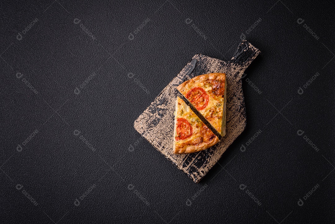 Deliciosa quiche com tomate, queijo, frango, especiarias e ervas sobre um fundo escuro de concreto