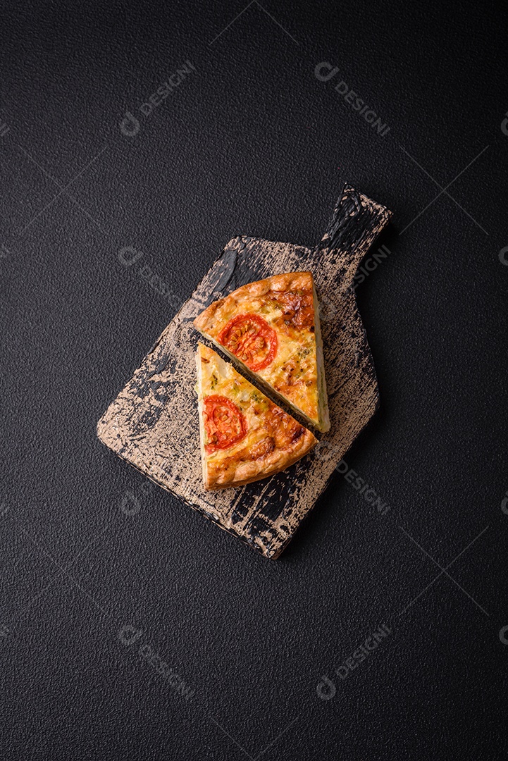 Deliciosa quiche com tomate, queijo, frango, especiarias e ervas sobre um fundo escuro de concreto