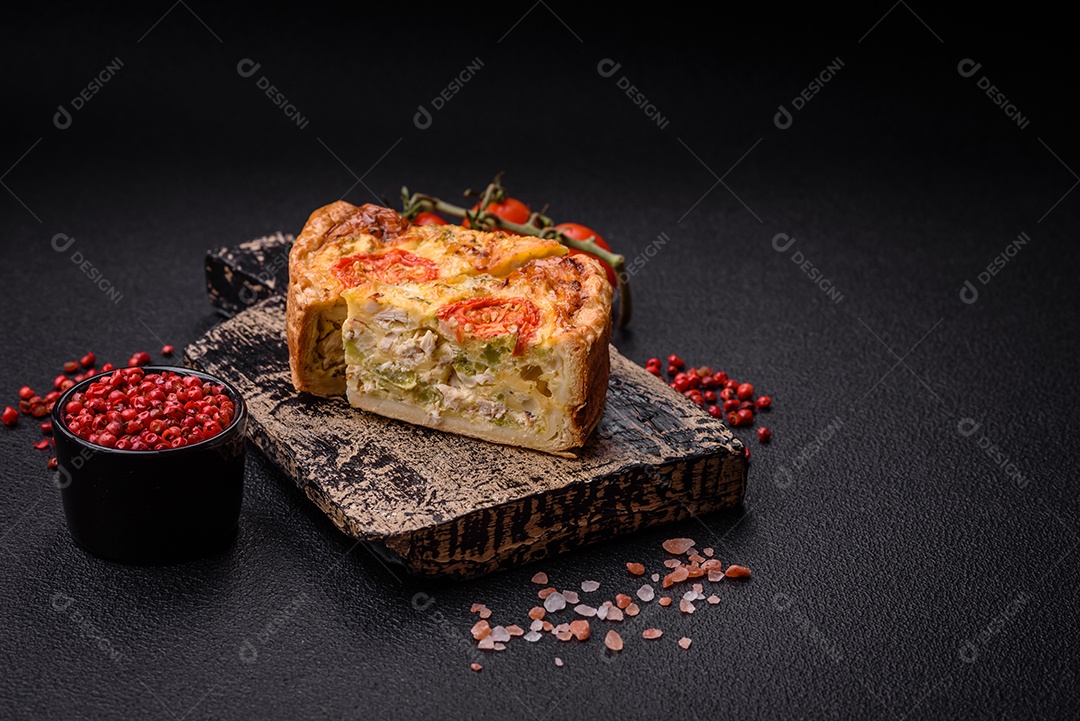 Deliciosa quiche com tomate, queijo, frango, especiarias e ervas sobre um fundo escuro de concreto