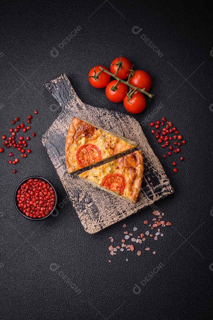 Deliciosa quiche com tomate, queijo, frango, especiarias e ervas sobre um fundo escuro de concreto