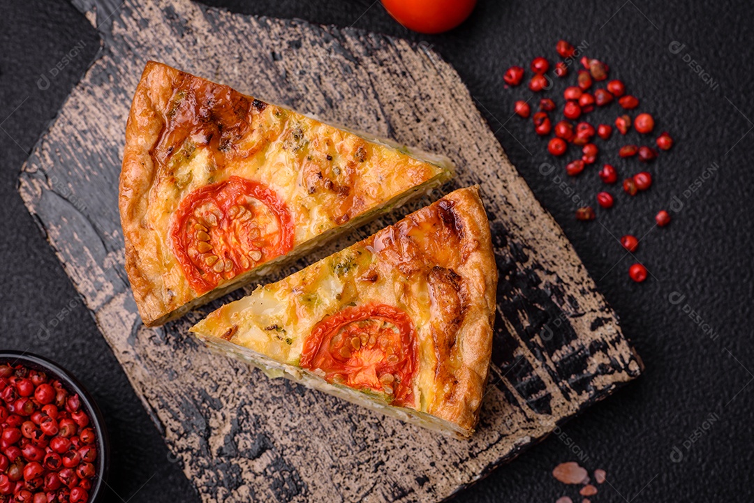 Deliciosa quiche com tomate, queijo, frango, especiarias e ervas sobre um fundo escuro de concreto