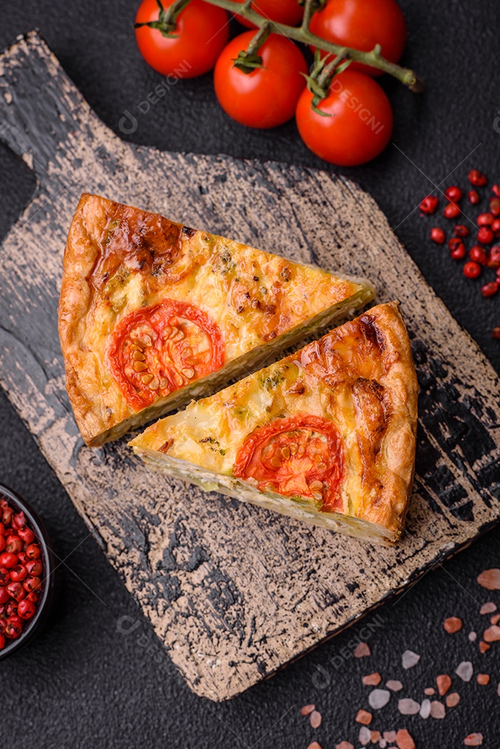 Deliciosa quiche com tomate, queijo, frango, especiarias e ervas sobre um fundo escuro de concreto