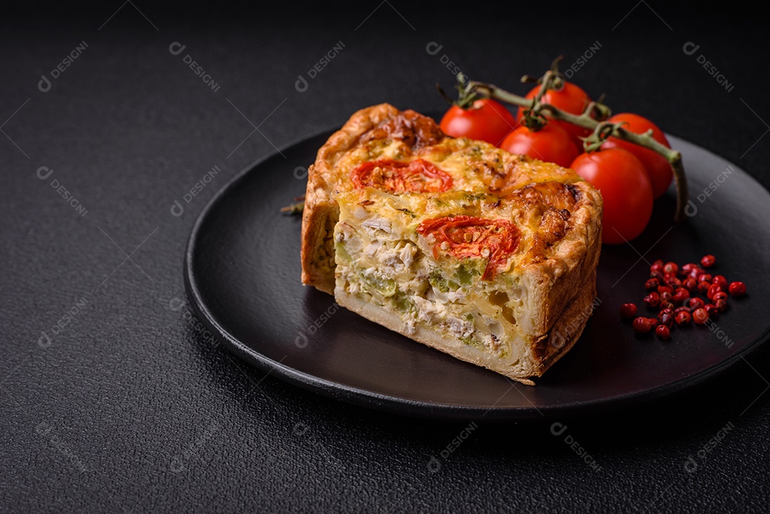 Deliciosa quiche com tomate, queijo, frango, especiarias e ervas sobre um fundo escuro de concreto