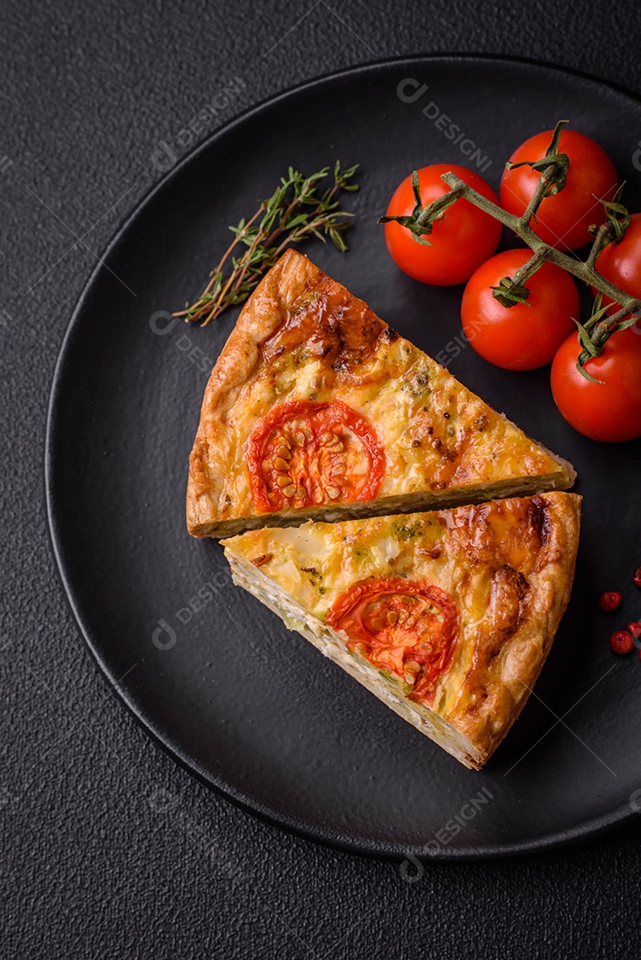 Deliciosa quiche com tomate, queijo, frango, especiarias e ervas sobre um fundo escuro de concreto
