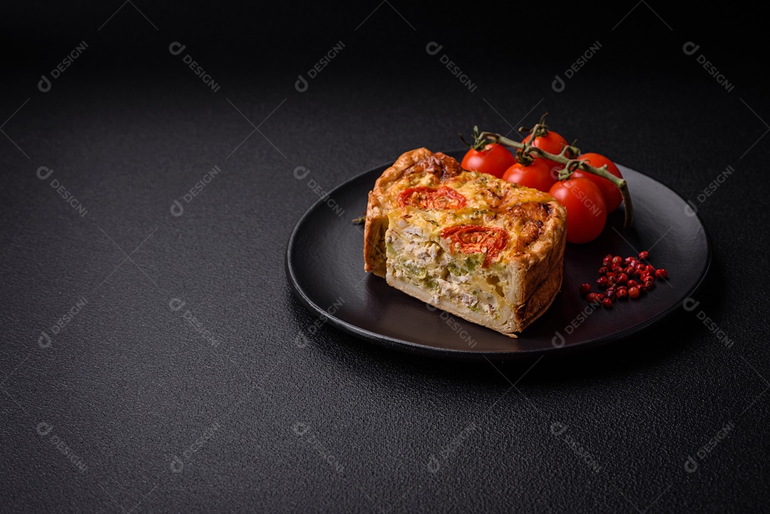 Deliciosa quiche com tomate, queijo, frango, especiarias e ervas sobre um fundo escuro de concreto