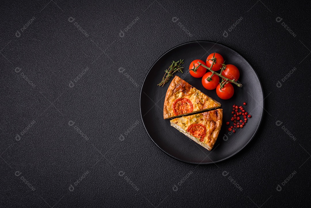 Deliciosa quiche com tomate, queijo, frango, especiarias e ervas sobre um fundo escuro de concreto