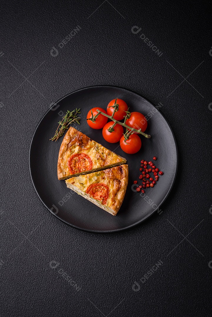 Deliciosa quiche com tomate, queijo, frango, especiarias e ervas sobre um fundo escuro de concreto