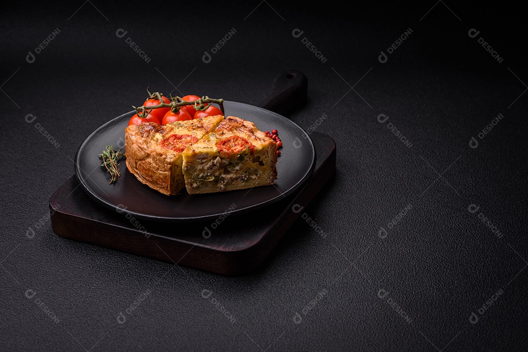 Deliciosa quiche com tomate, queijo, frango, especiarias e ervas sobre um fundo escuro de concreto