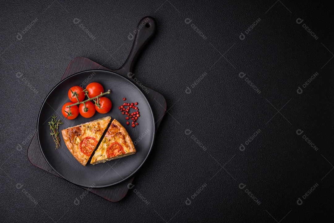 Deliciosa quiche com tomate, queijo, frango, especiarias e ervas sobre um fundo escuro de concreto