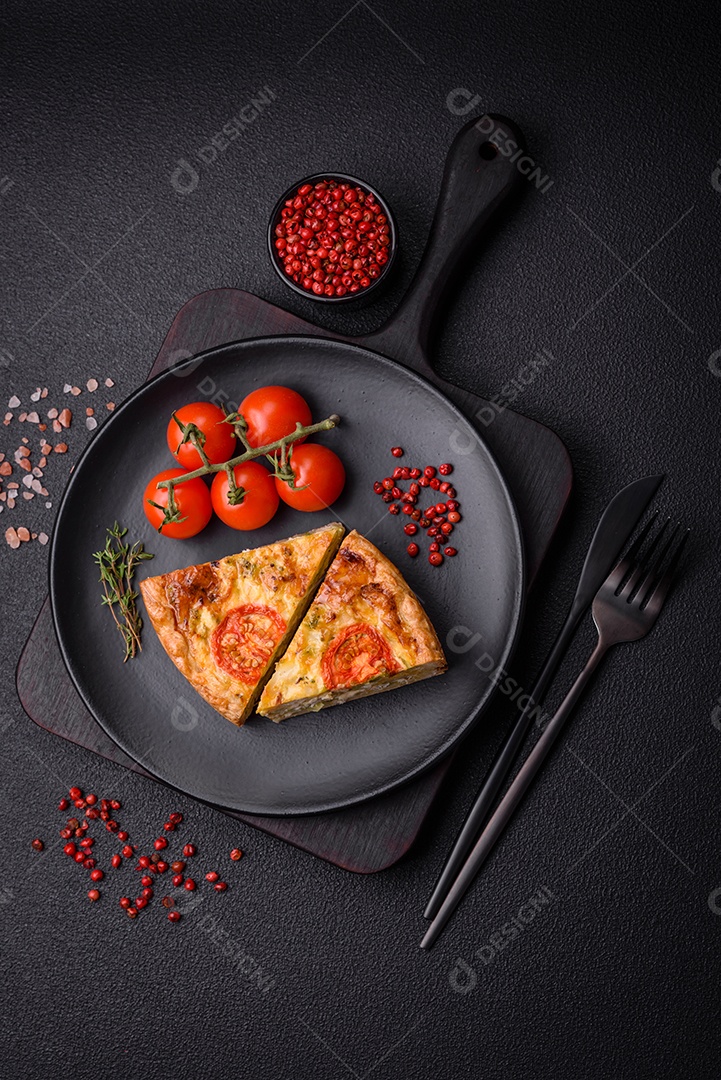 Deliciosa quiche com tomate, queijo, frango, especiarias e ervas sobre um fundo escuro de concreto