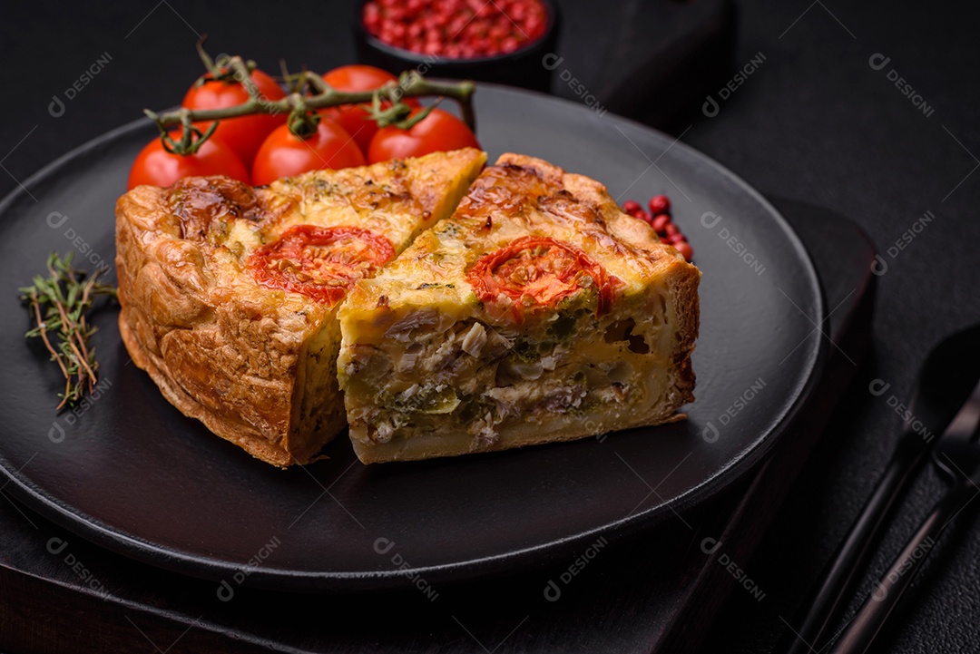 Deliciosa quiche com tomate, queijo, frango, especiarias e ervas sobre um fundo escuro de concreto