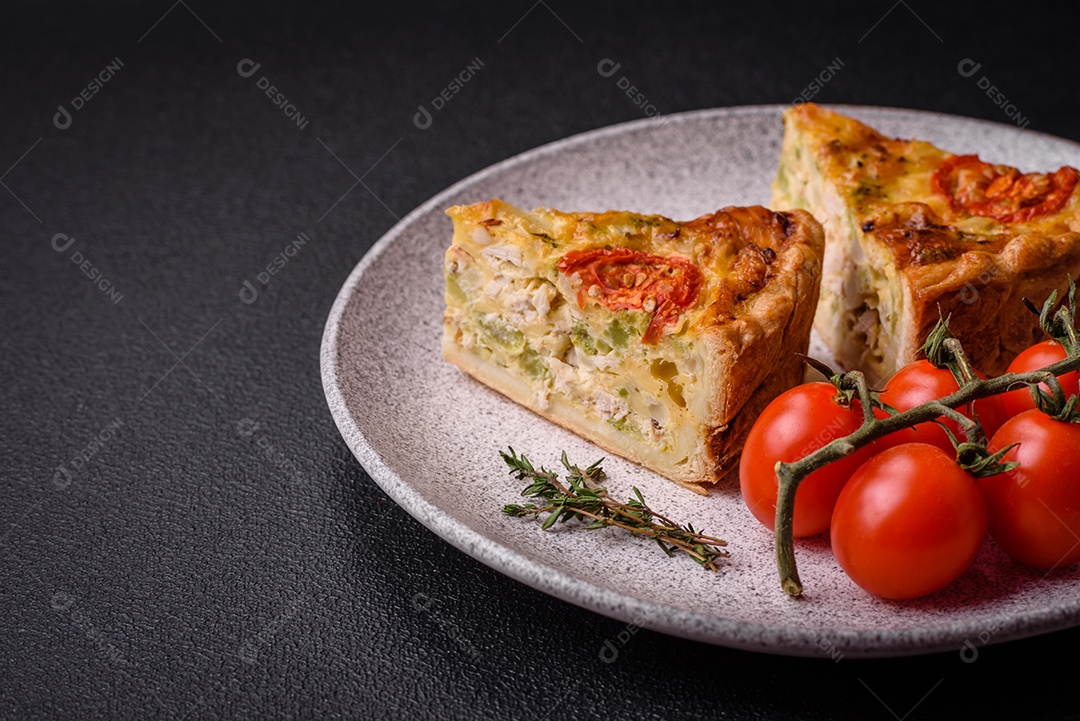 Deliciosa quiche com tomate, queijo, frango, especiarias e ervas sobre um fundo escuro de concreto