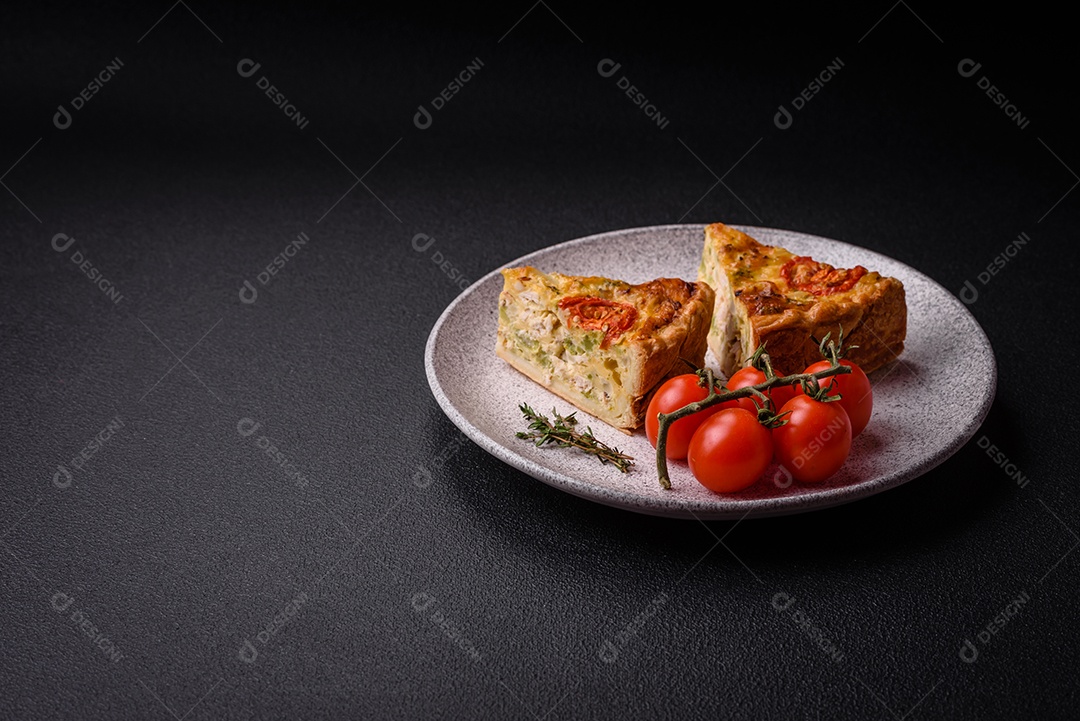 Deliciosa quiche com tomate, queijo, frango, especiarias e ervas sobre um fundo escuro de concreto