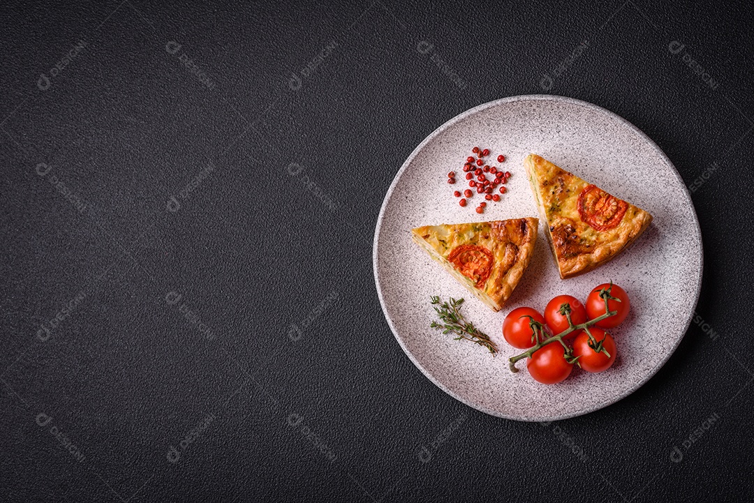 Deliciosa quiche com tomate, queijo, frango, especiarias e ervas sobre um fundo escuro de concreto