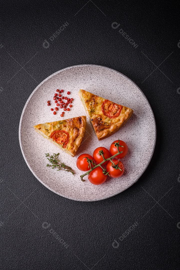 Deliciosa quiche com tomate, queijo, frango, especiarias e ervas sobre um fundo escuro de concreto