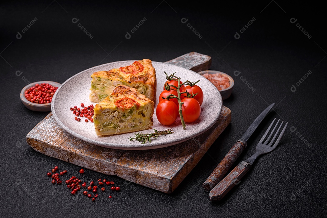 Deliciosa quiche com tomate, queijo, frango, especiarias e ervas sobre um fundo escuro de concreto