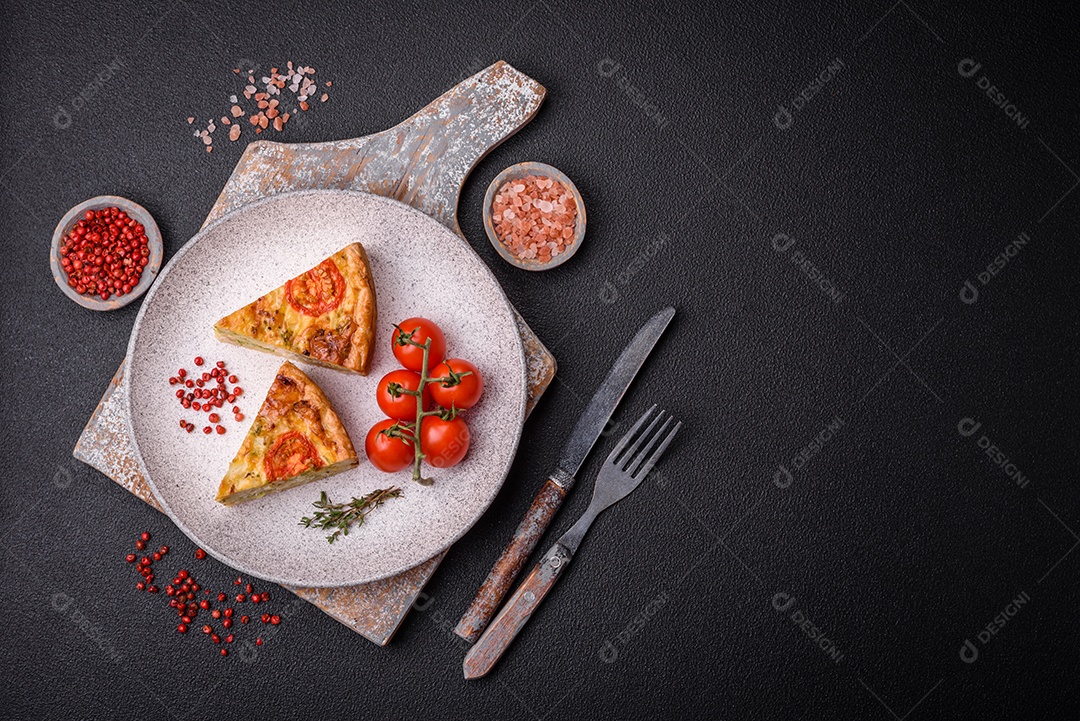 Deliciosa quiche com tomate, queijo, frango, especiarias e ervas sobre um fundo escuro de concreto