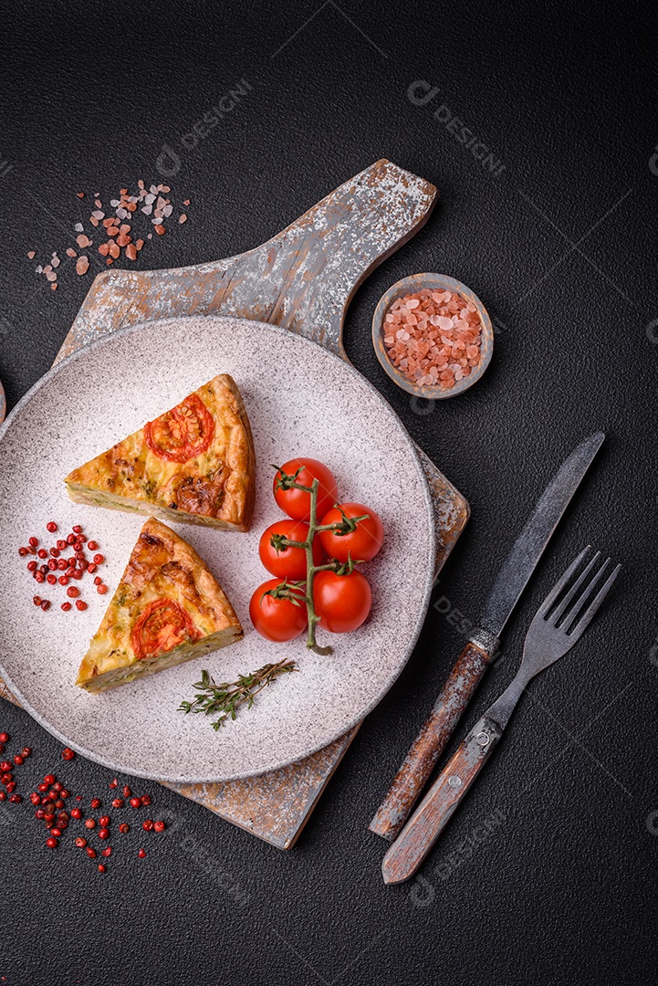 Deliciosa quiche com tomate, queijo, frango, especiarias e ervas sobre um fundo escuro de concreto