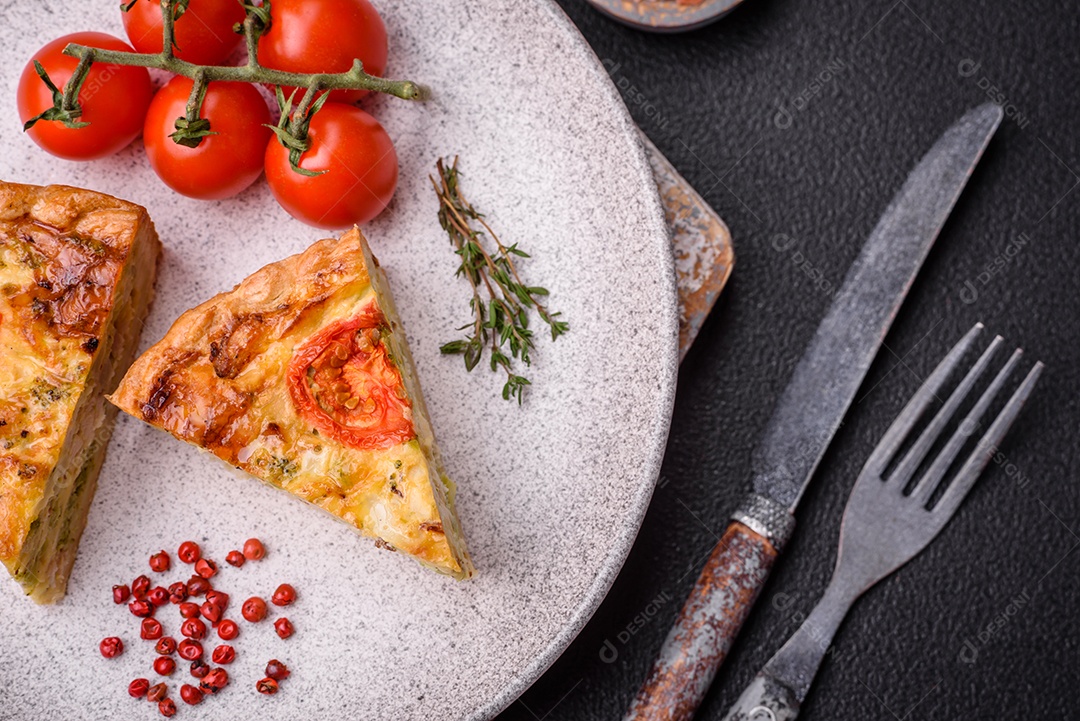 Deliciosa quiche com tomate, queijo, frango, especiarias e ervas sobre um fundo escuro de concreto