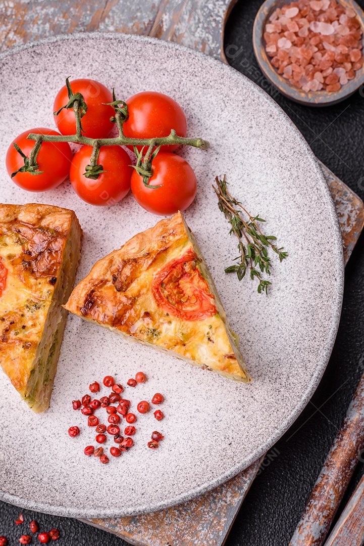 Deliciosa quiche com tomate, queijo, frango, especiarias e ervas sobre um fundo escuro de concreto