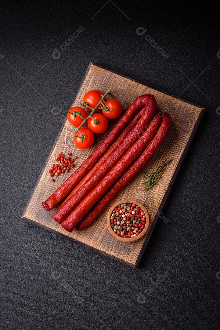 Deliciosas salsichas de caça defumadas com sal, especiarias e ervas sobre um fundo escuro de concreto